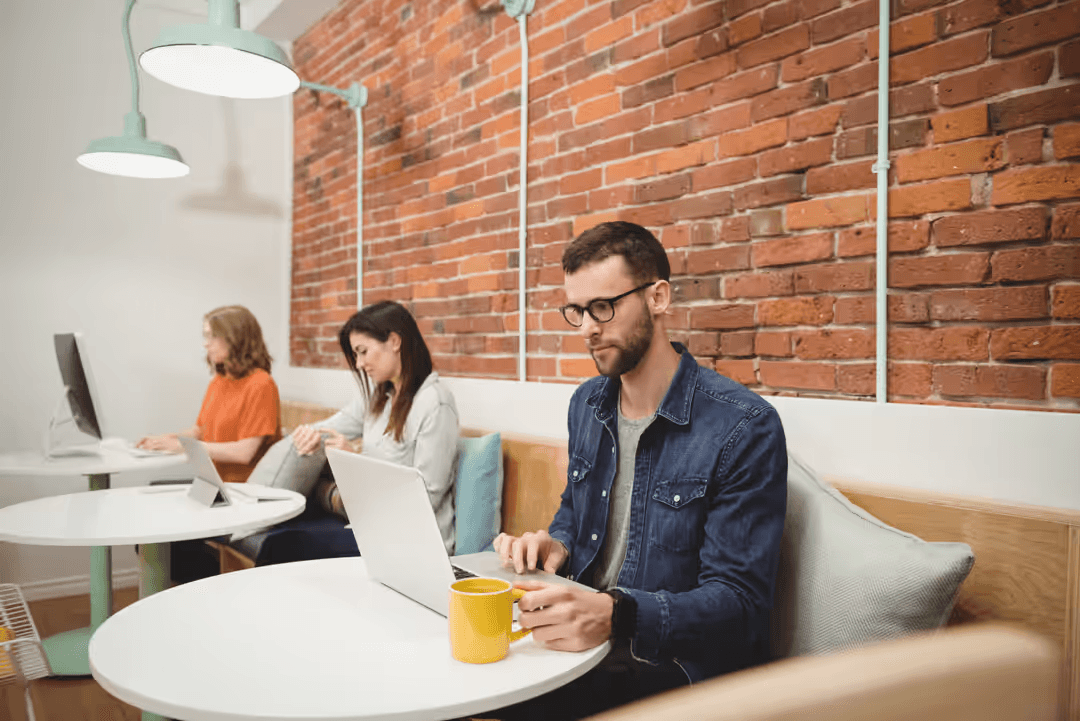 Three people working at desks on their laptops working - Retail marketing strategy tips and tricks to drive sales and save money - Image