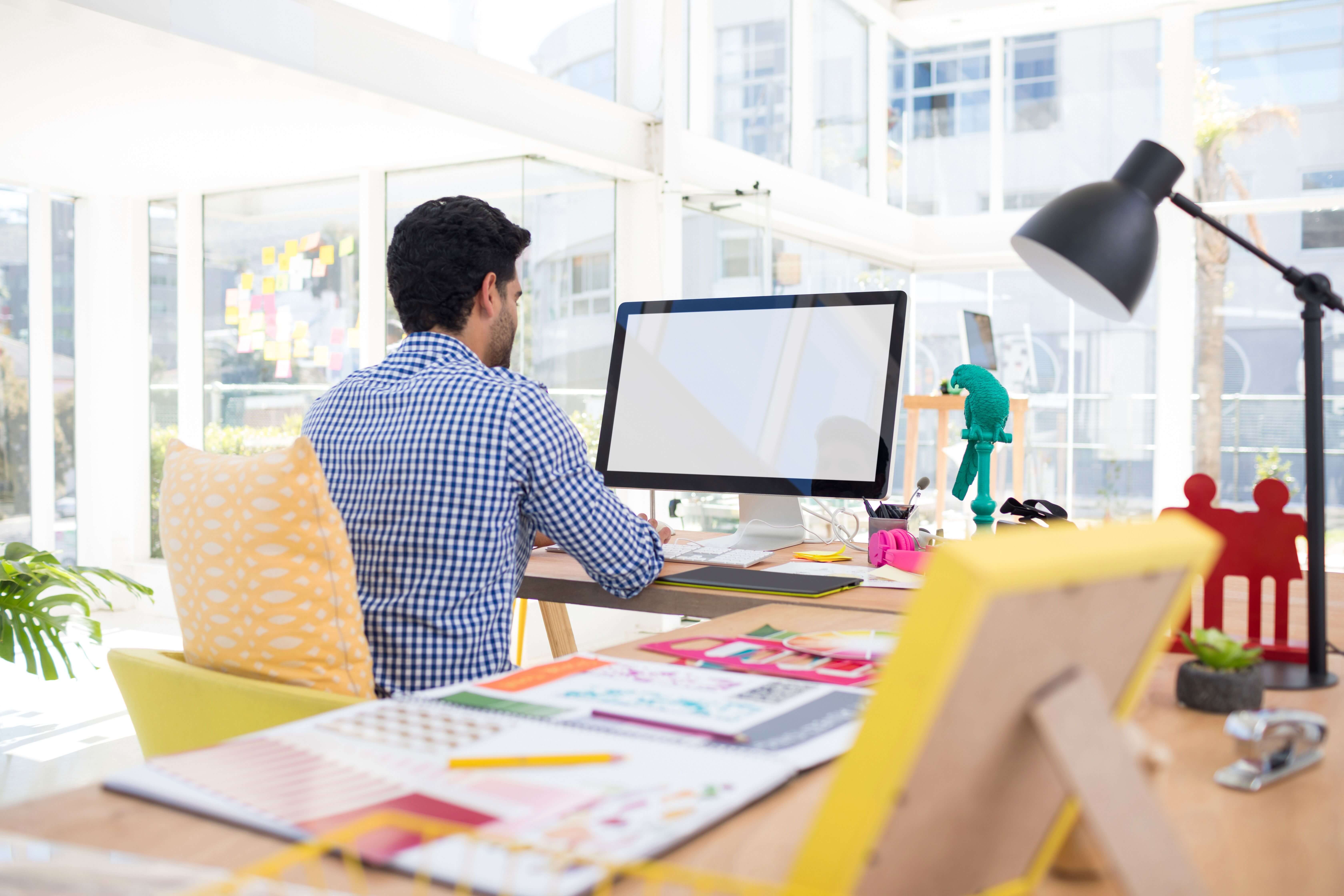 Image of a man working on a computer taken from behind - Graphic design trend predictions - Image