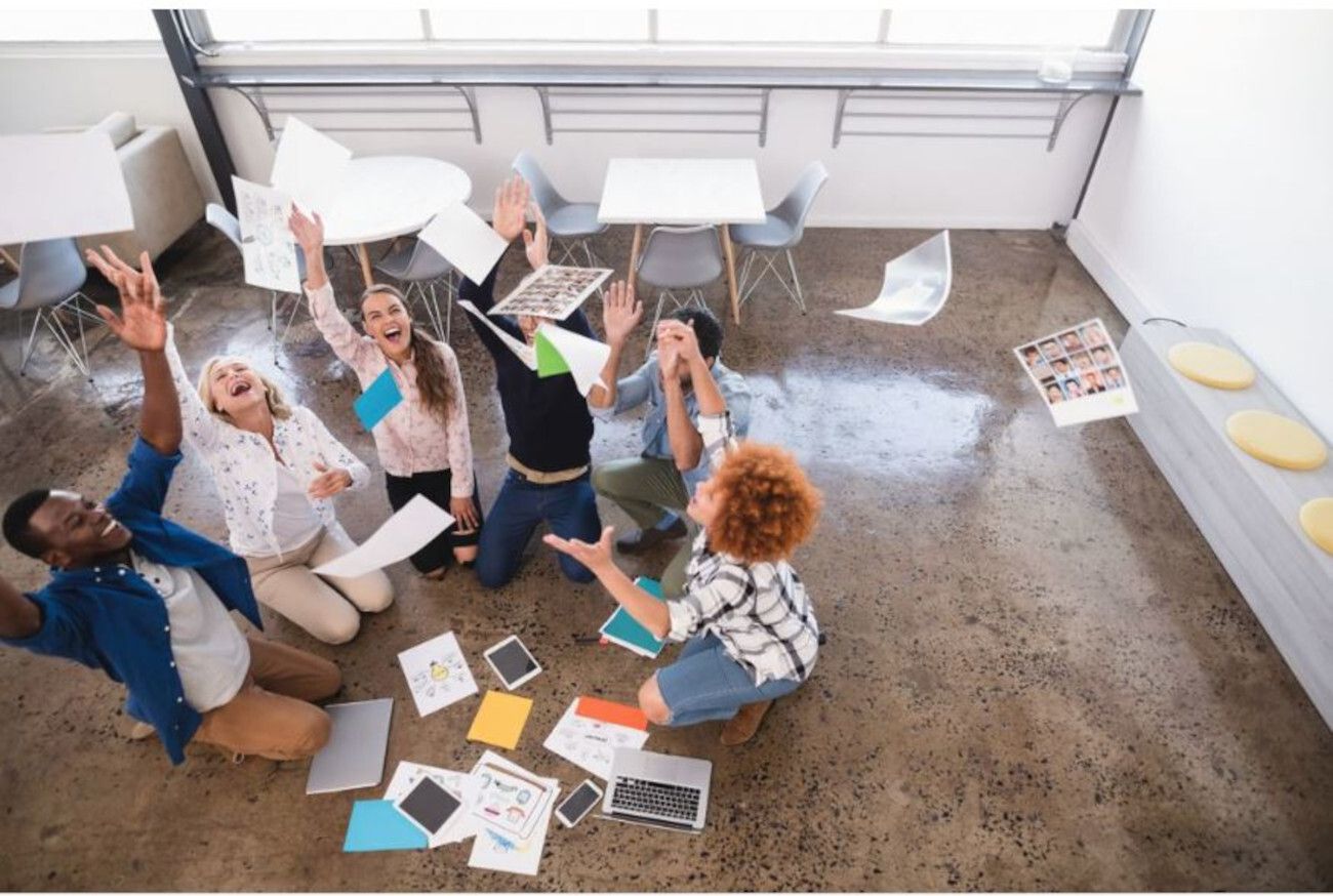 Happy colleagues are sitting on the floor and throwing documents - Persistent marketing myths expert roundup - Image