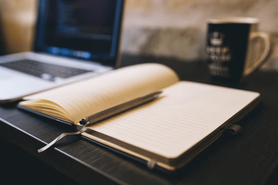 Image of a laptop, coffee cup, notebook and a pen on a desk - Expert online marketing tips to improve your digital strategy and make more money - Image
