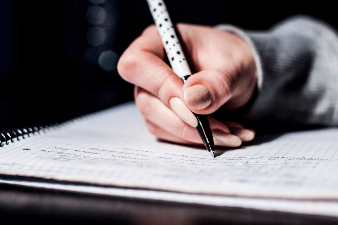 Woman writing on a notepad with a black pen - Retail marketing strategy tips and tricks to drive sales and save money - Image