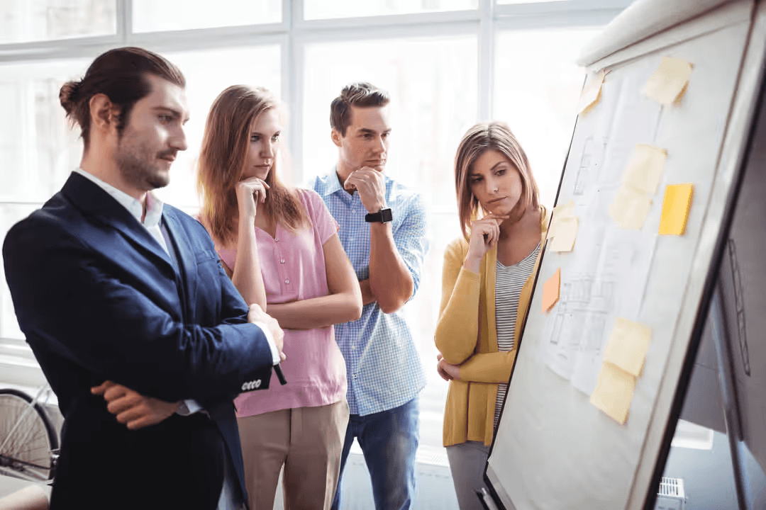 Image of three people looking at a board with sticky notes - How to design a good business website: 18 key principles - Image