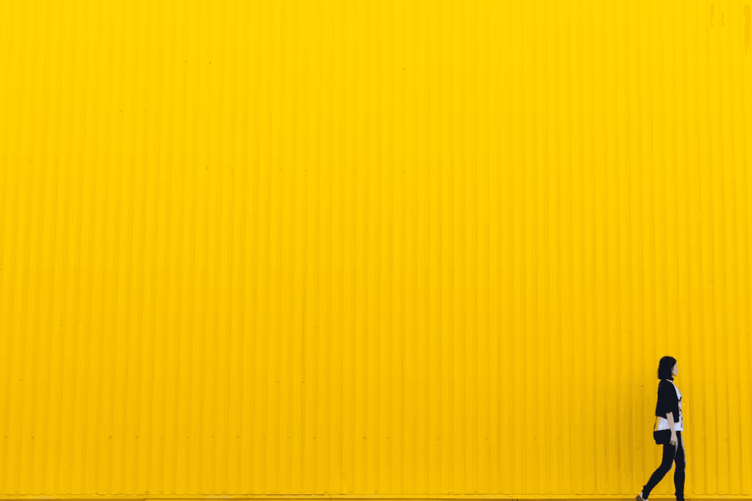 Large yellow wall with woman walking in front - How to create the best modern color scheme for your website - Image