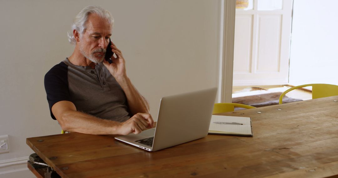 Senior Man Multitasking on Laptop and Phone at Home - Free Images, Stock Photos and Pictures on Pikwizard.com