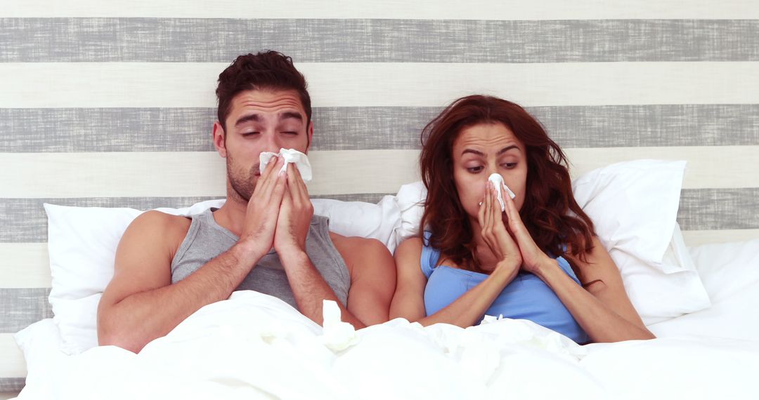 Sick Couple in Bed Blowing Nose with Tissues
