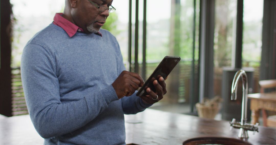 Middle-aged African American Man Using Tablet in Modern Kitchen - Free Images, Stock Photos and Pictures on Pikwizard.com