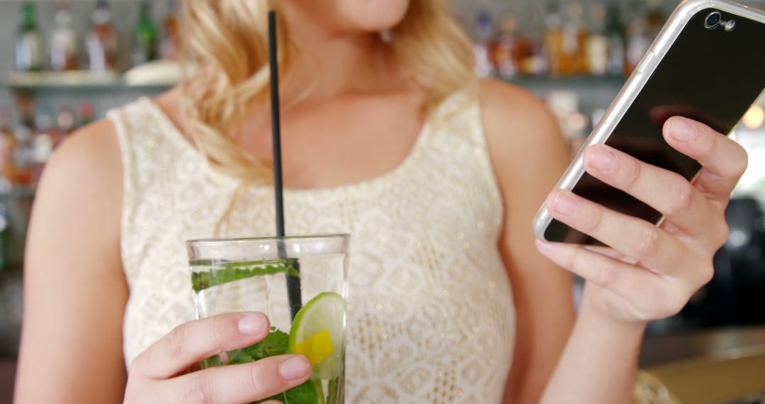 Woman Drinking Mojito While Using Smartphone at Bar - Free Images, Stock Photos and Pictures on Pikwizard.com