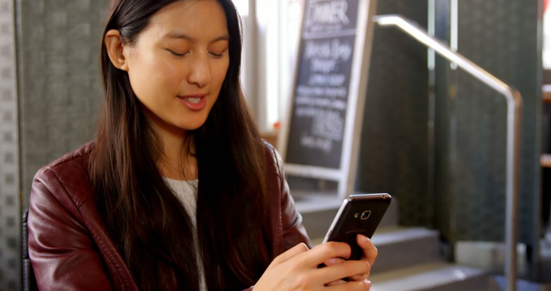 Woman Engaged with Smartphone in Modern Cafe
