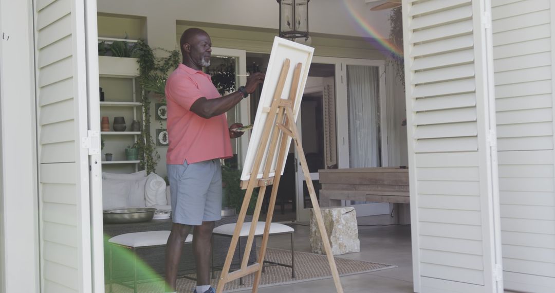 Smiling Man Painting on Easel in Sunlit Room - Free Images, Stock Photos and Pictures on Pikwizard.com