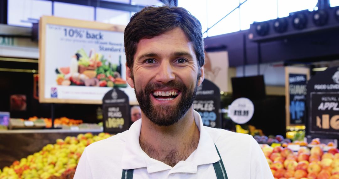 Smiling fruit market worker in front of colorful produce display - Free Images, Stock Photos and Pictures on Pikwizard.com