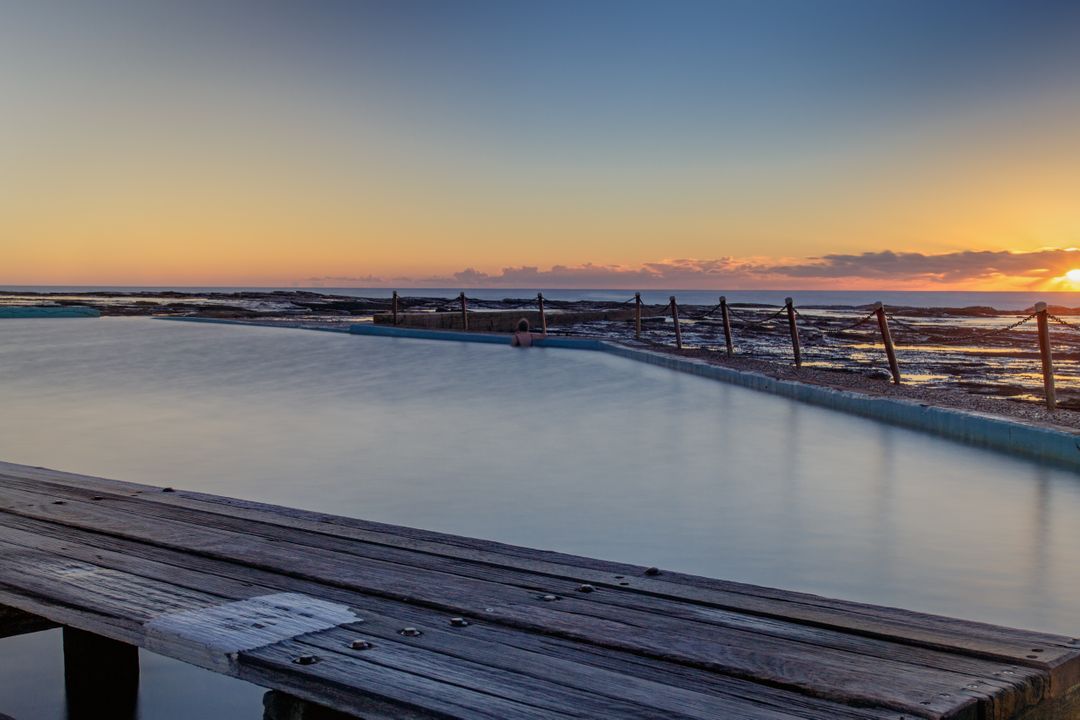 Calm Ocean Pool at Sunrise with Wooden Deck - Free Images, Stock Photos and Pictures on Pikwizard.com