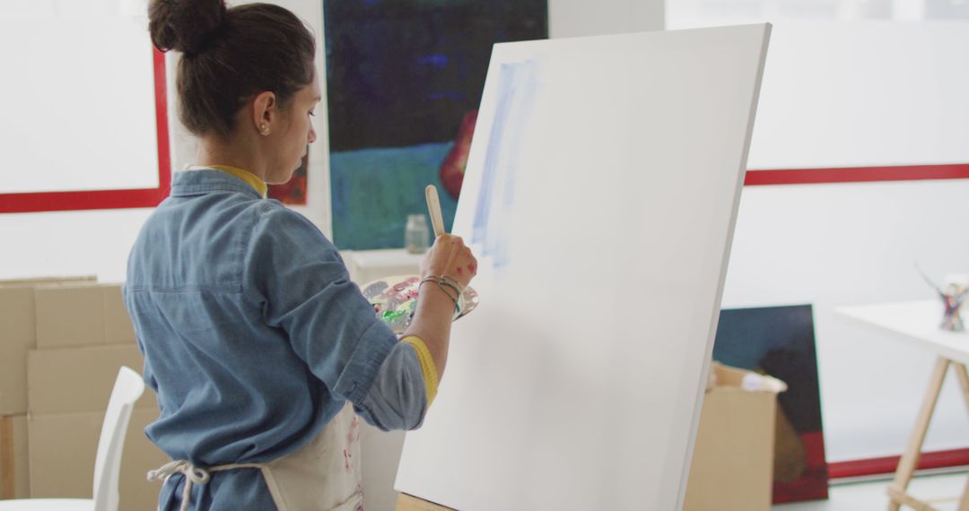 Image of biracial female artist painting in studio - Free Images, Stock Photos and Pictures on Pikwizard.com