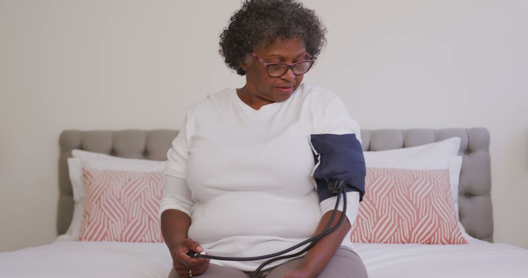 Elderly Woman Monitoring Blood Pressure at Home on Bed - Free Images, Stock Photos and Pictures on Pikwizard.com