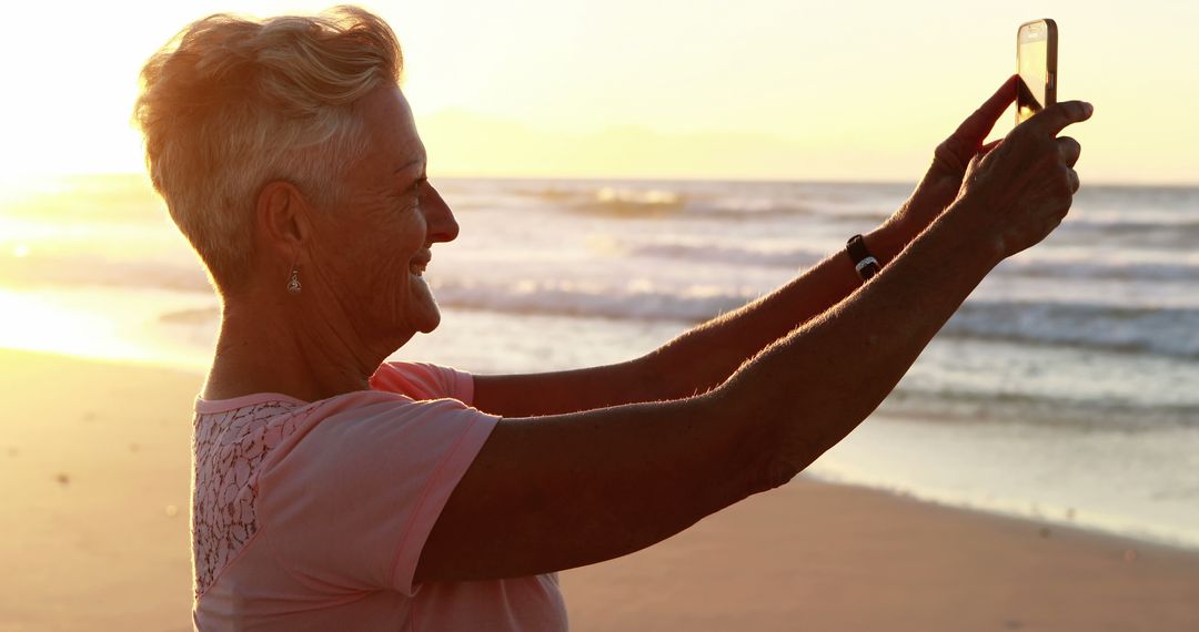 Senior Woman Taking Selfie on Beach at Sunset - Free Images, Stock Photos and Pictures on Pikwizard.com