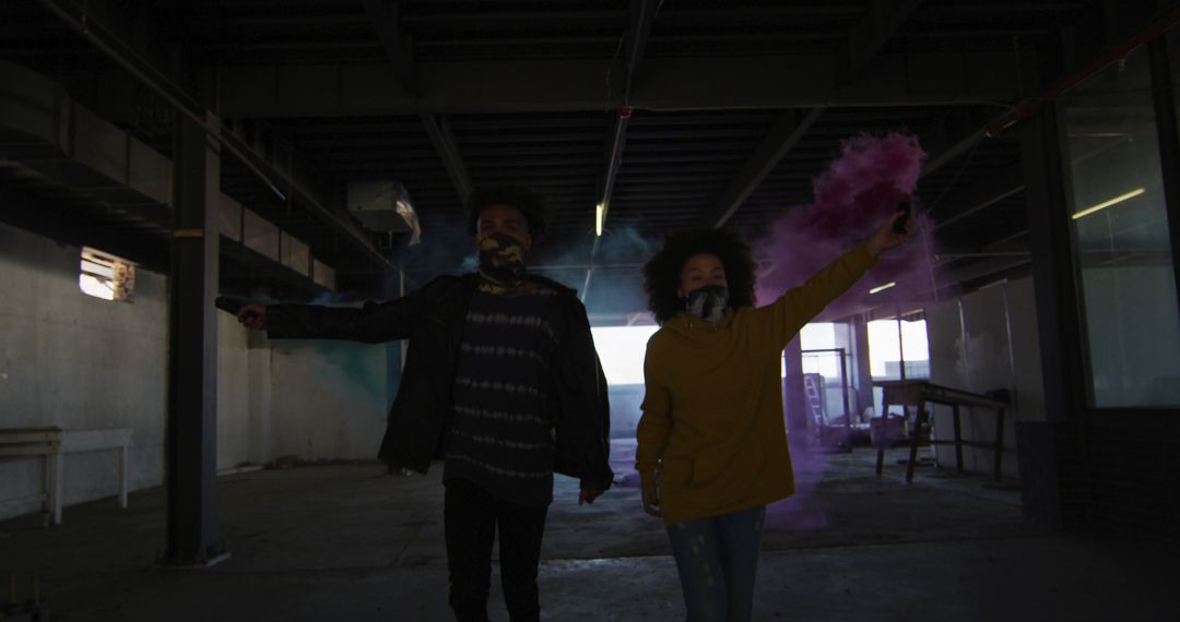 Young couple holding colored smoke and dancing in abandoned building - Free Images, Stock Photos and Pictures on Pikwizard.com