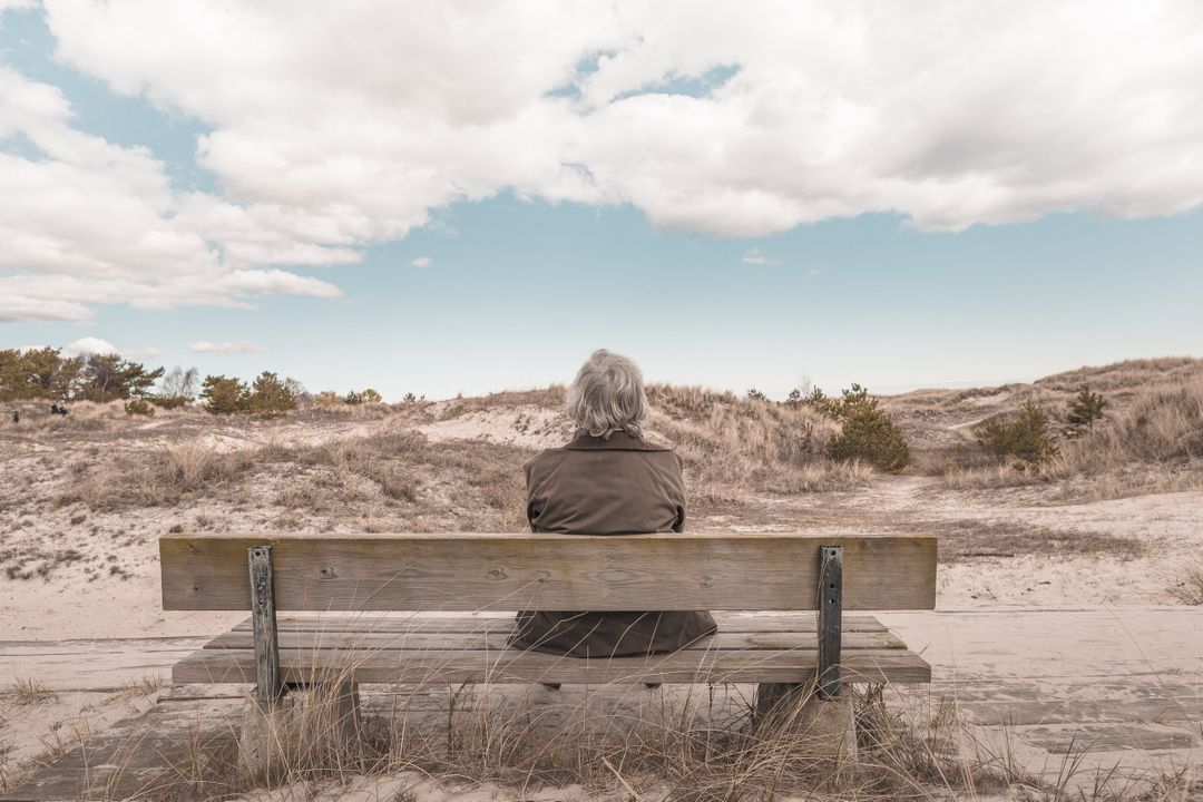 Elderly Woman Sitting on Bench Looking at Peaceful Sand Dunes - Free Images, Stock Photos and Pictures on Pikwizard.com