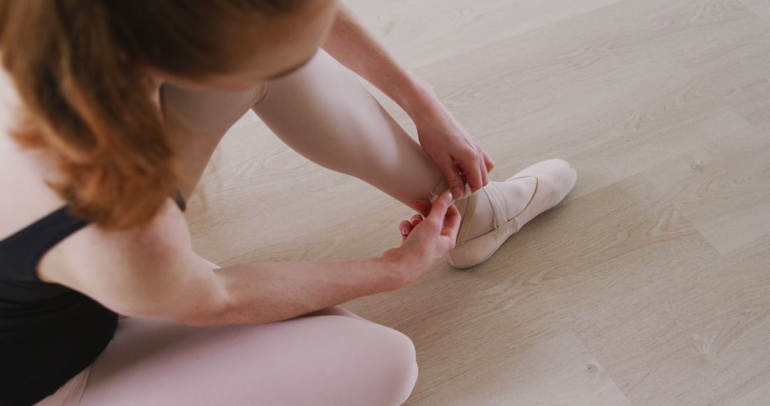 Ballet Dancer Preparing Pointe Shoes on Wooden Floor - Free Images, Stock Photos and Pictures on Pikwizard.com