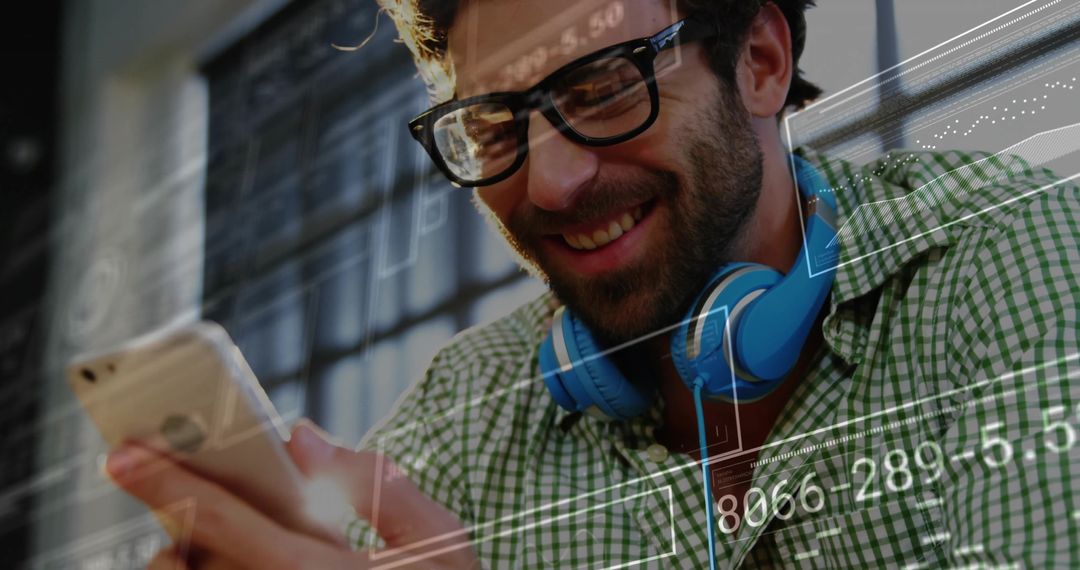Smiling Man with Headphones Browsing Smartphone in Tech Environment