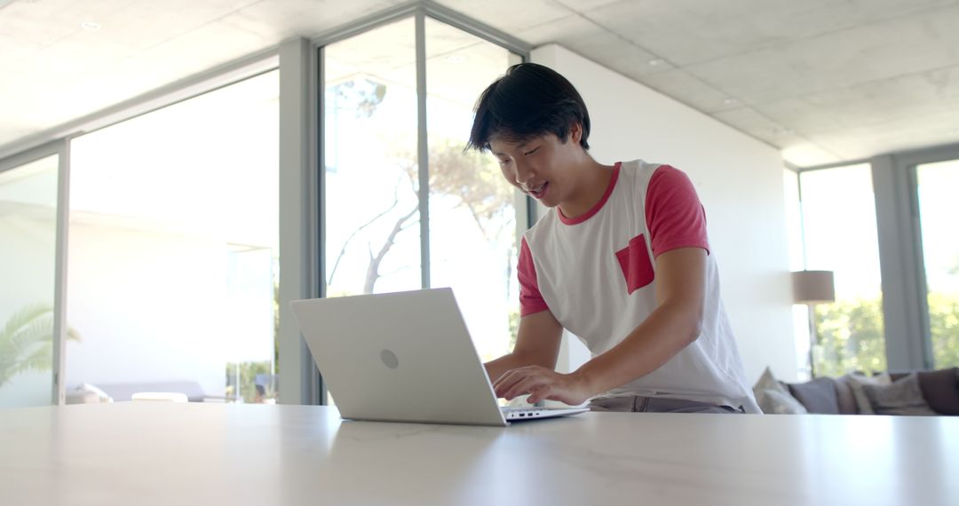 Asian College Student Focused on Typing Work at Home