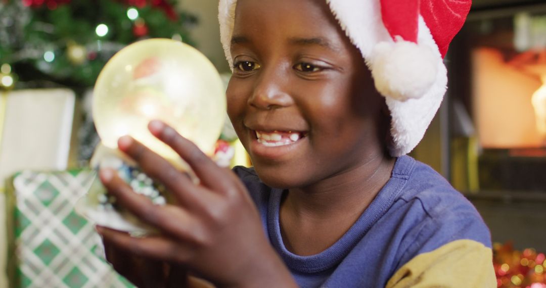 Joyful Boy Holding a Snow Globe Amid Festive Christmas Scene - Free Images, Stock Photos and Pictures on Pikwizard.com