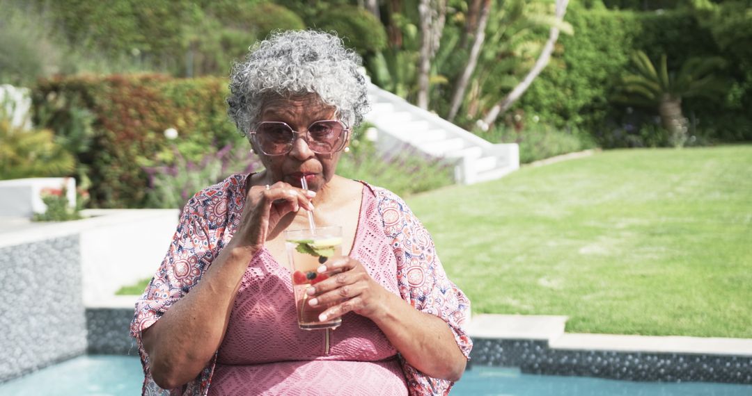 Senior Woman Enjoying Refreshing Drink by Poolside in Summery Environment