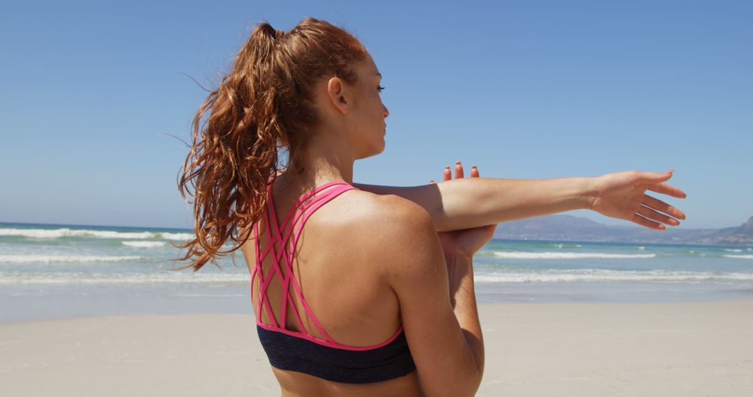 Athletic Woman Stretching Shoulder on Sandy Beach at Sunrise - Free Images, Stock Photos and Pictures on Pikwizard.com