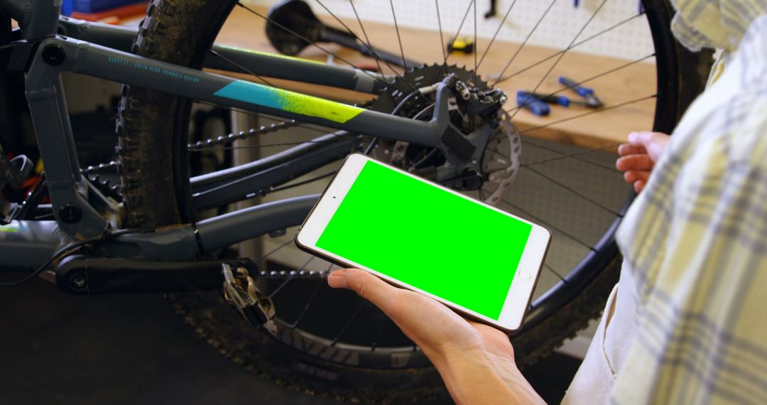 Mechanic Using Tablet With Green Screen in Bicycle Repair Shop