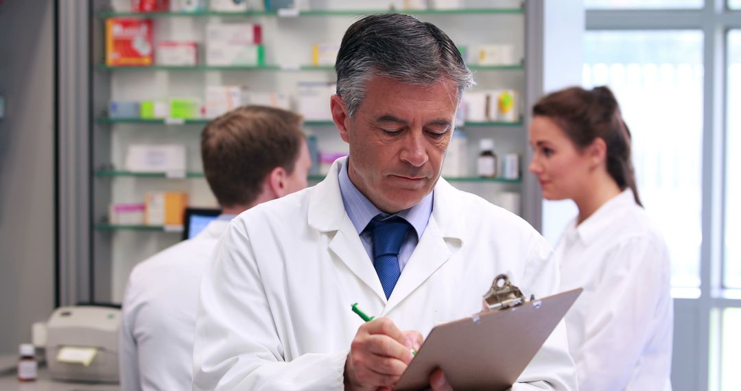 Senior Pharmacist Writing Notes in Busy Pharmacy - Free Images, Stock Photos and Pictures on Pikwizard.com