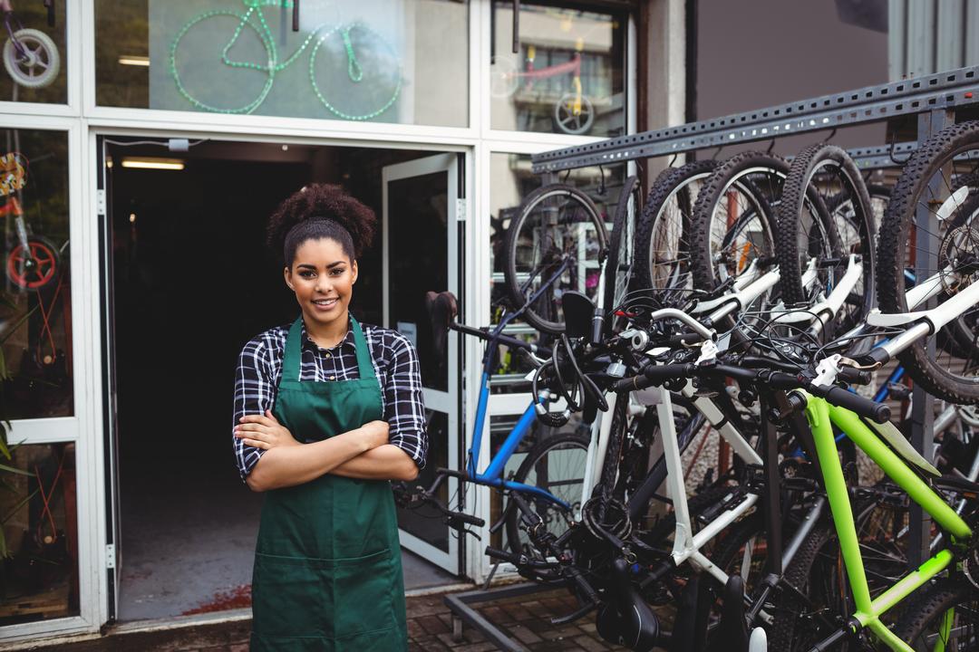 Smiling Female Mechanic Standing with Arms Crossed in Bicycle Workshop - Free Images, Stock Photos and Pictures on Pikwizard.com