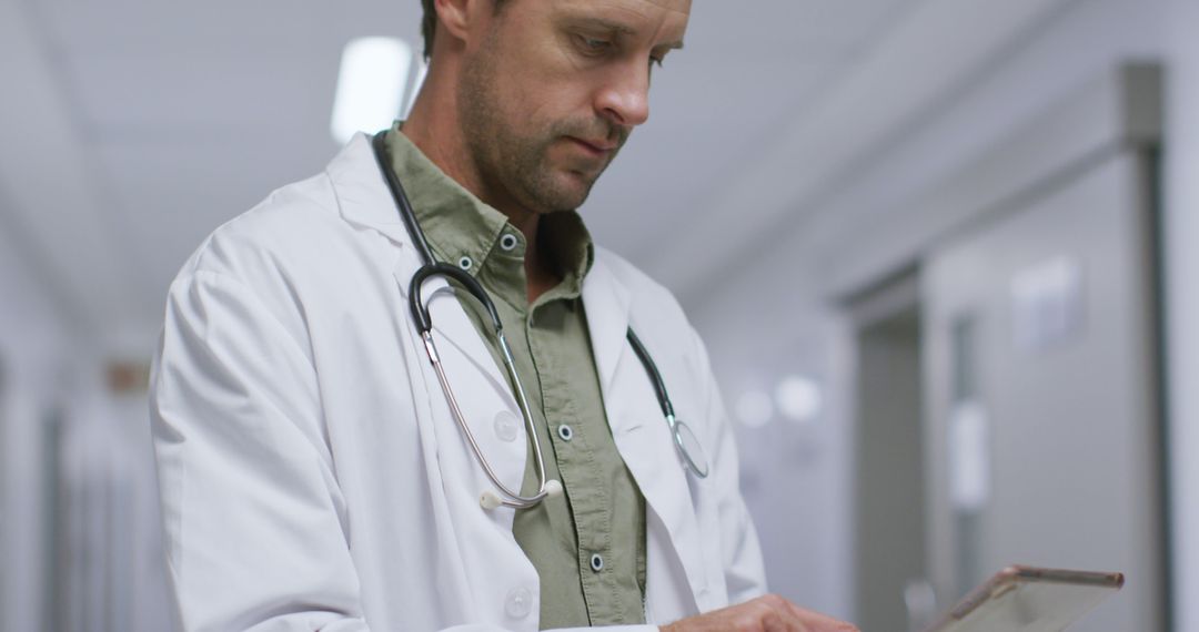 Caucasian Doctor Using Digital Tablet in Hospital Corridor - Free Images, Stock Photos and Pictures on Pikwizard.com