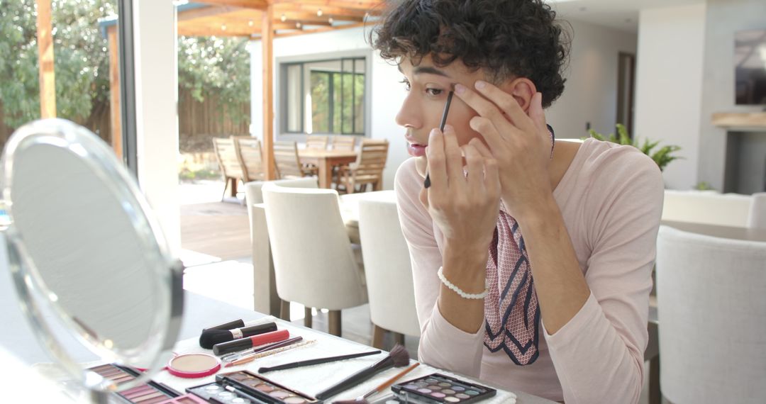 Man Perfecting Eyeliner with Makeup Tools in Home Dining Area
