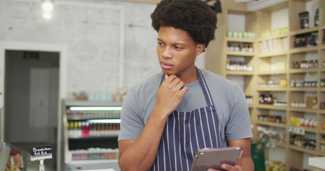 Thoughtful Barista Using Tablet in Modern Coffee Shop