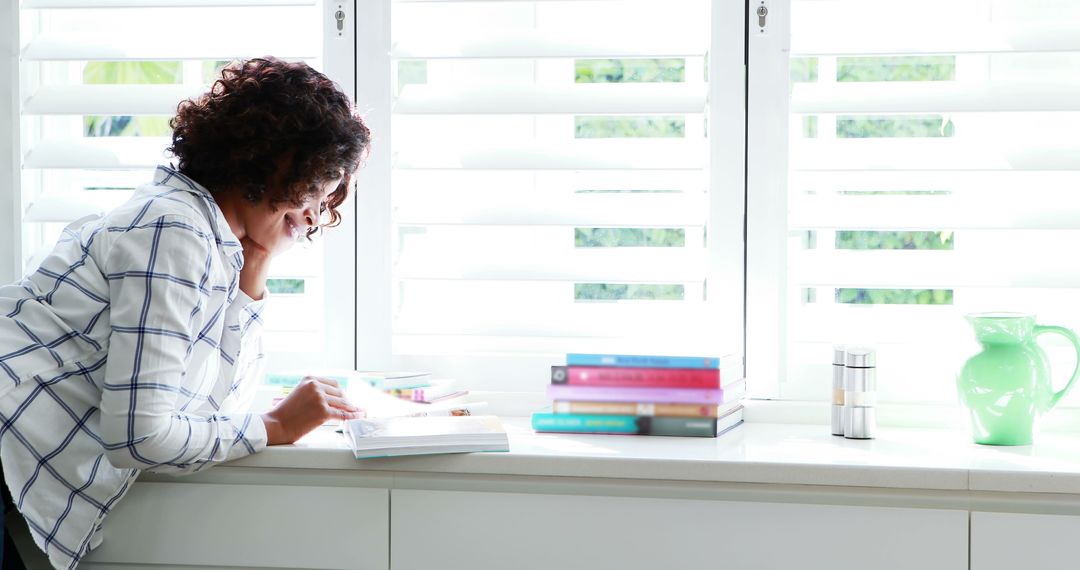 Woman Reading Book by Window in Bright Room - Free Images, Stock Photos and Pictures on Pikwizard.com