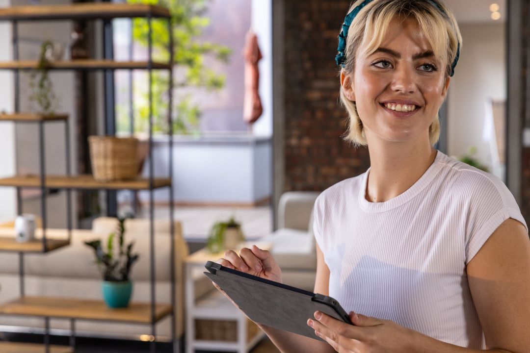 Smiling Woman Using Tablet in Modern Loft Interior with Natural Light