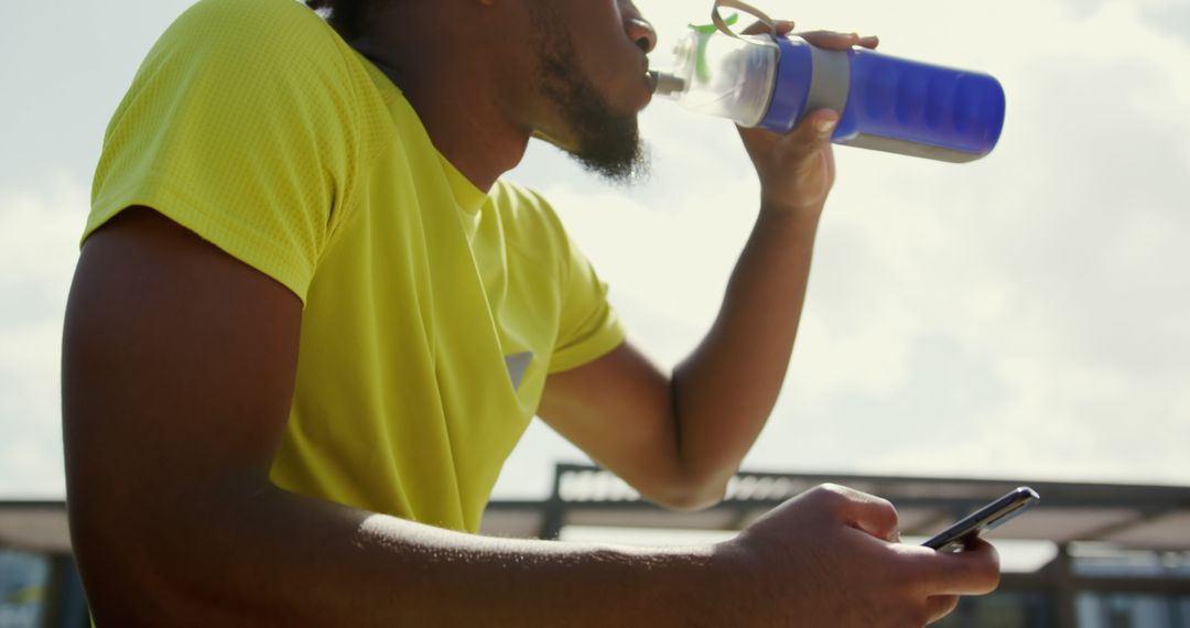 Male Athlete Drinking Water while Using Smartphone Outdoor - Free Images, Stock Photos and Pictures on Pikwizard.com