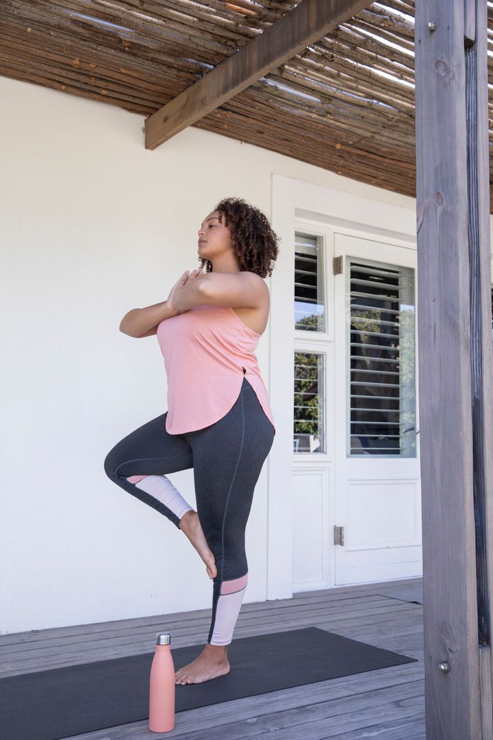 Woman Practicing Tree Pose Under Pergola with Water Bottle