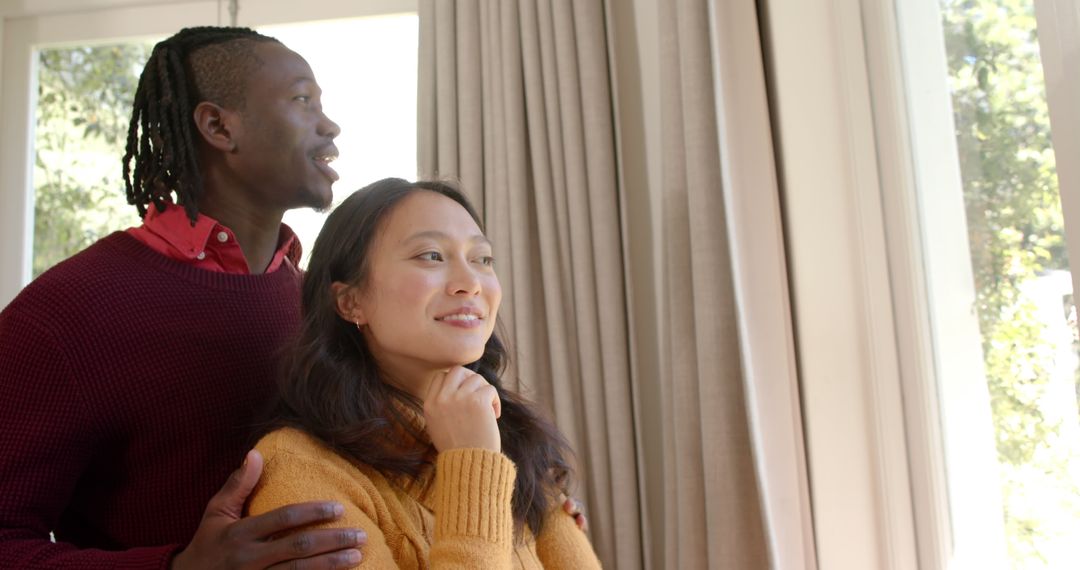 Cheerful Diverse Couple Embracing and Watching View Out Window