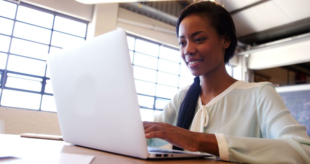 Smiling African American Woman Working on Laptop in Modern Office - Free Images, Stock Photos and Pictures on Pikwizard.com