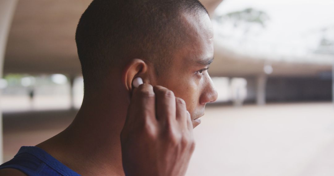 Young Man Using Wireless Earbuds in Urban Setting - Free Images, Stock Photos and Pictures on Pikwizard.com