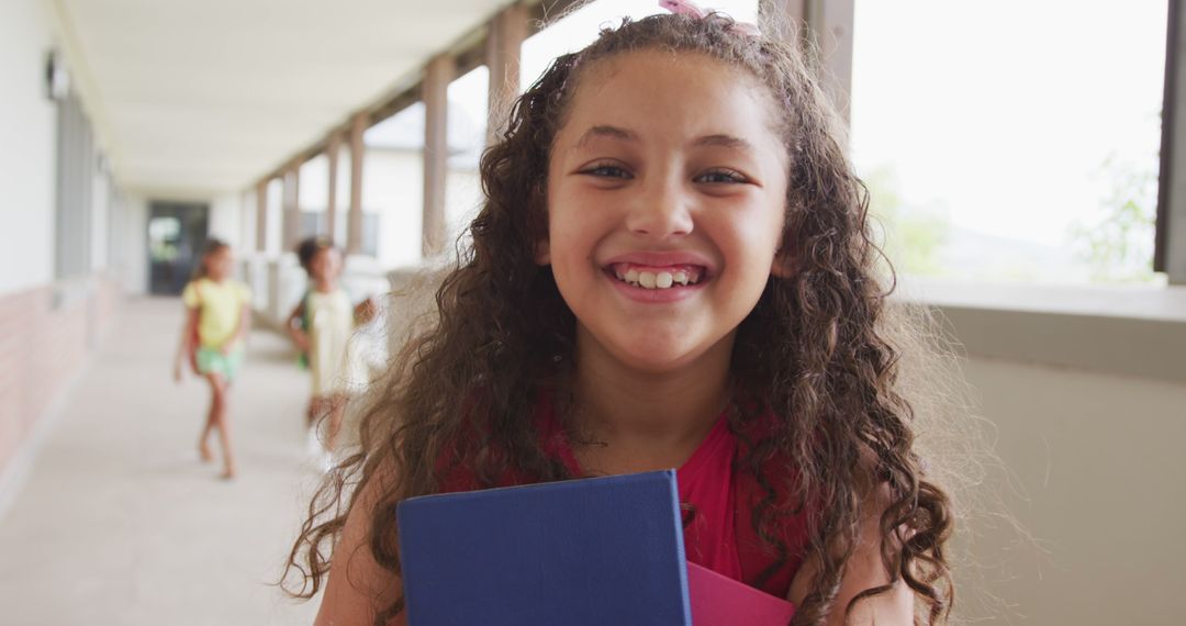 Smiling Young Girl Holding Books in School Hallway - Free Images, Stock Photos and Pictures on Pikwizard.com