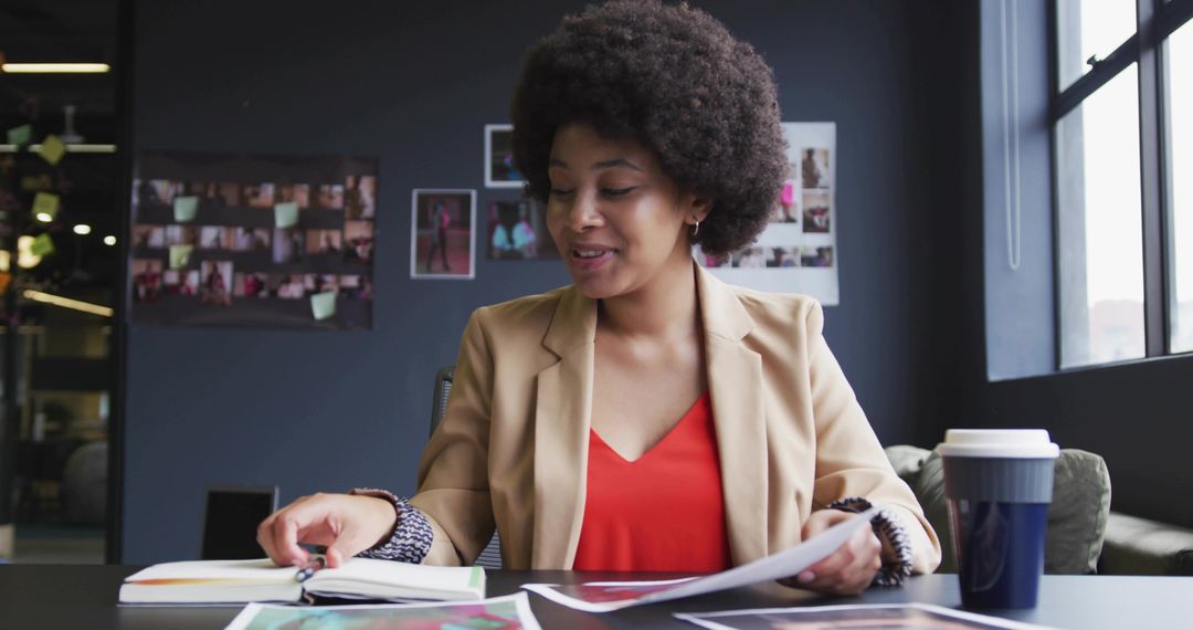 Creative professional reviewing printed layouts at modern studio desk with coffee