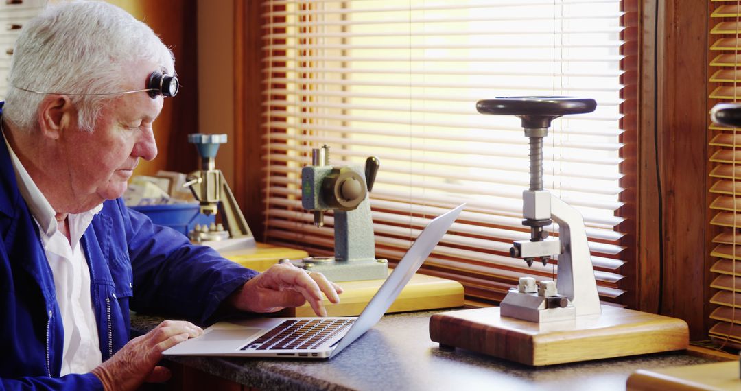 Senior Horologist Using Laptop in Traditional Workshop