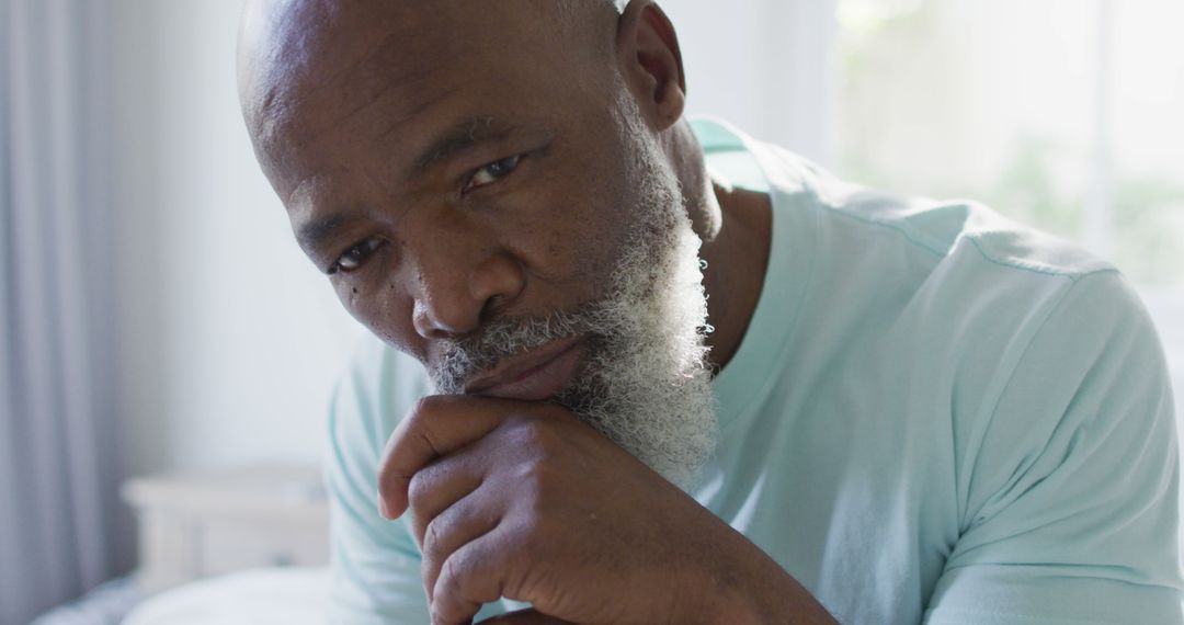 Thoughtful Elderly Man Contemplating Indoors Sitting with Hand on Chin - Free Images, Stock Photos and Pictures on Pikwizard.com