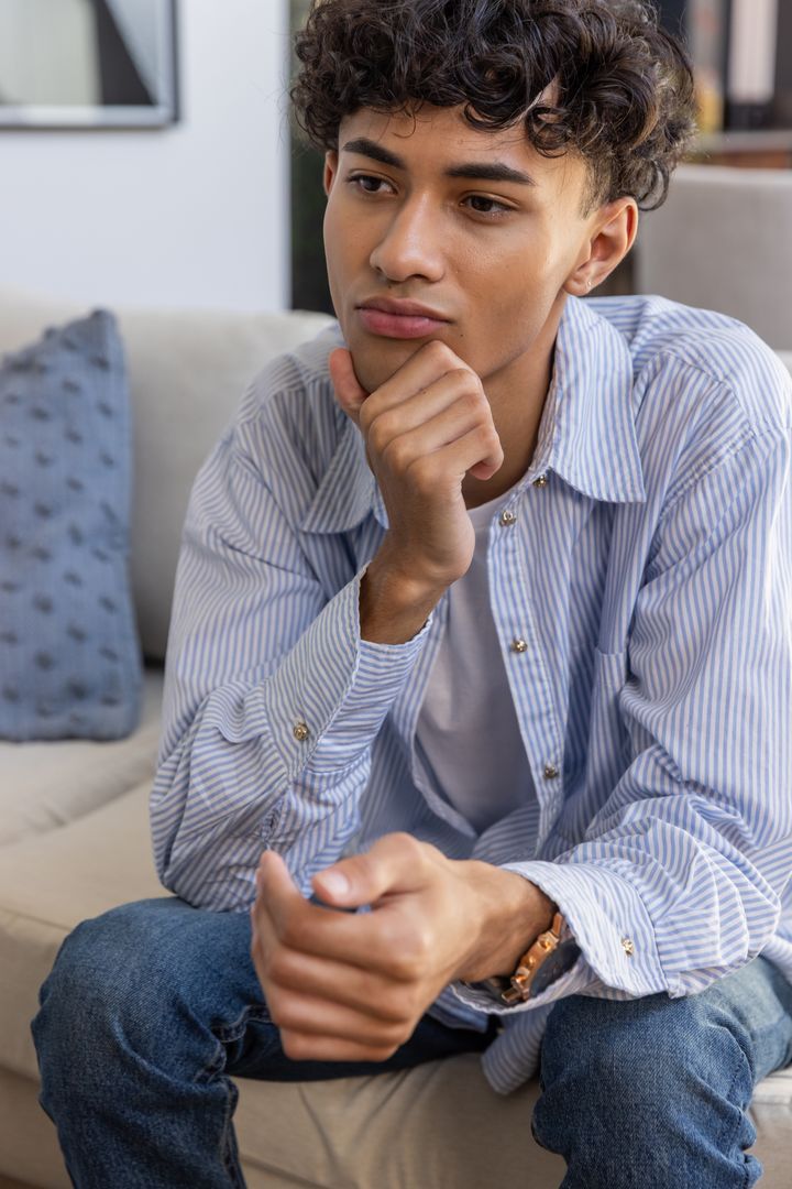 Young Man in Thought Relaxing on Modern Sofa at Home