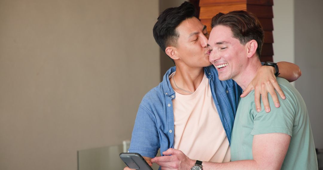 Diverse Gay Couple Laughing Together with Smartphone at Home