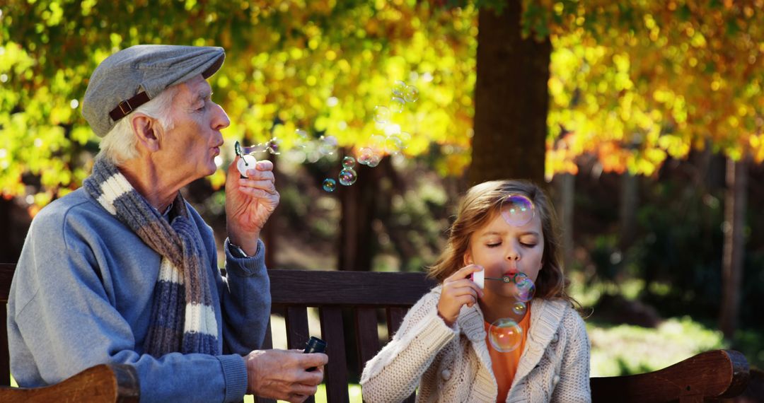 Grandfather and Granddaughter Blowing Bubbles in Autumn Park - Free Images, Stock Photos and Pictures on Pikwizard.com