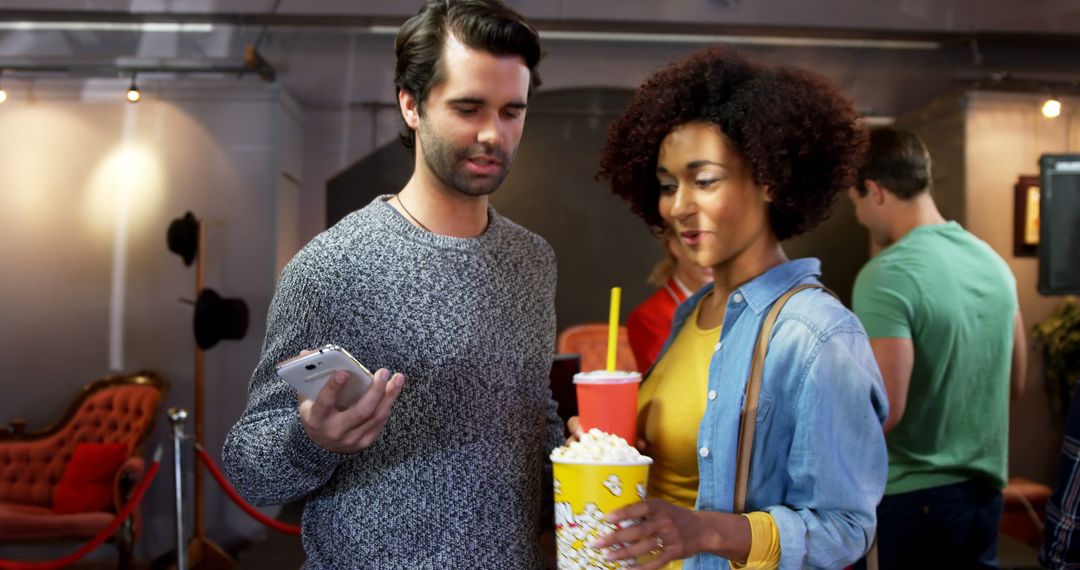Friends Watching Video on Smartphone with Popcorn and Drinks