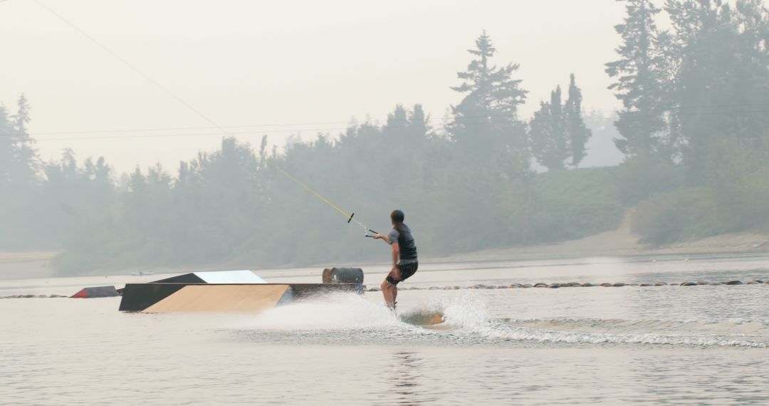 Person Wakeboarding on Calm Lake with Misty Background - Free Images, Stock Photos and Pictures on Pikwizard.com