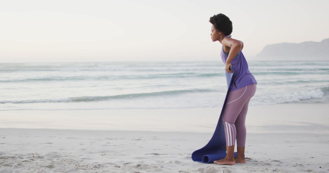 Woman Setting Up Yoga Mat on Beach for Outdoor Exercise - Free Images, Stock Photos and Pictures on Pikwizard.com