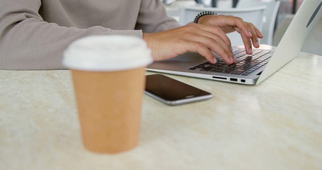 Person Typing on Laptop with Coffee Cup and Smartphone on Table - Free Images, Stock Photos and Pictures on Pikwizard.com